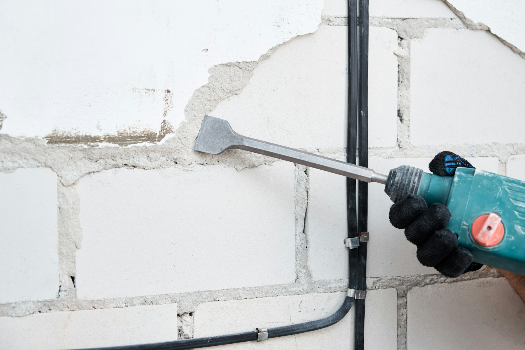 Man with demolition hammer remove stucco from wall. Renovation concept